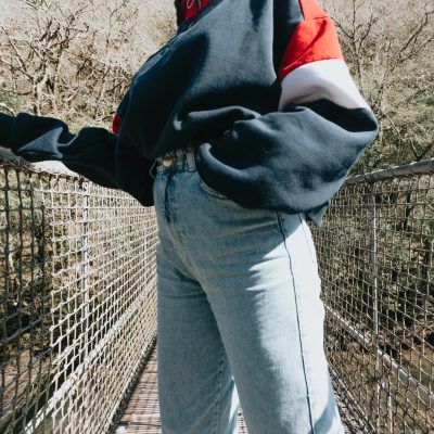 A close up of a woman wearing mom jeans on a bridge over the river